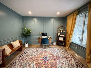 Home office featuring a decorative wall and wood finished floors