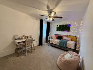 Carpeted bedroom featuring a textured ceiling, baseboards, and a ceiling fan