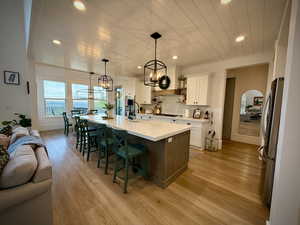 Kitchen with a chandelier, stainless steel appliances, wood ceiling, light wood finished floors, and white cabinetry