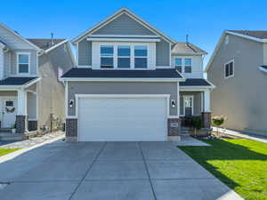 View of front of house featuring brick siding, concrete driveway, an attached garage, and a front yard