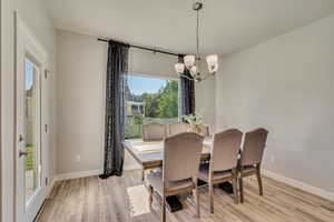 Dining space featuring a chandelier, baseboards, and light wood finished floors