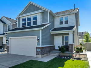 Craftsman inspired home with brick siding, an attached garage, driveway, and a front lawn