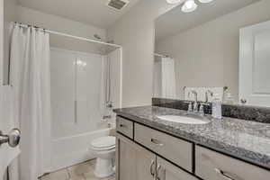 Full bath with vanity, shower / tub combo, tile patterned flooring, and toilet