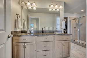 Full bath featuring a shower stall, double vanity, and tile patterned floors