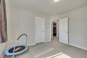 Unfurnished bedroom with washing machine and dryer, carpet flooring, and baseboards