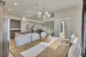 Dining area featuring light wood finished floors, recessed lighting, a chandelier, and stairs