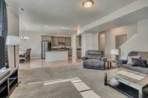 Living room featuring baseboards, a chandelier, recessed lighting, light wood-style floors, and light colored carpet