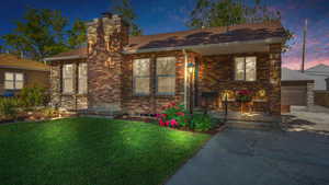 Bungalow with a front yard, a chimney, a porch, a shingled roof, and brick siding