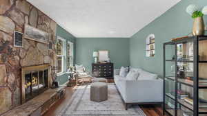 Living room with wood finished floors, a textured ceiling, a fireplace, and baseboards