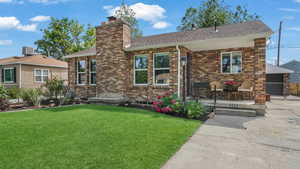 View of front of home featuring a chimney, a shingled roof, a porch, brick siding, and central AC