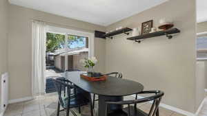 Dining area with light tile patterned floors, baseboards, and a textured ceiling