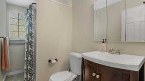 Full bath with toilet, vanity, tile patterned floors, a shower with shower curtain, and baseboards