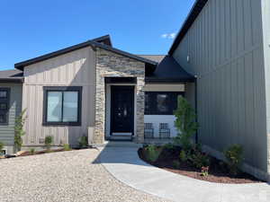 View of exterior entry with board and batten siding and stone siding