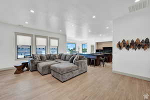 Living room with recessed lighting, light wood finished floors, and baseboards