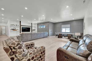 Living area with healthy amount of natural light, light wood finished floors, and recessed lighting