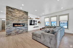 Living area featuring wood finished floors, a stone fireplace, recessed lighting, and baseboards