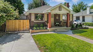 Bungalow-style house featuring covered porch, brick siding, and a chimney