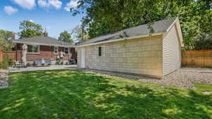 Rear view of house with an outbuilding, a patio area, and brick siding