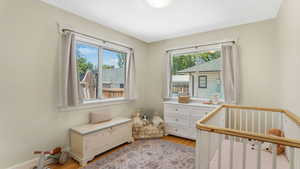 Bedroom with light wood-style floors and a nursery area