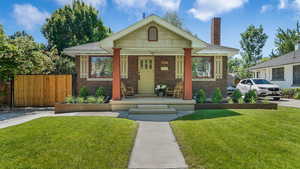 Bungalow-style house with brick siding, a porch, a chimney, and roof with shingles