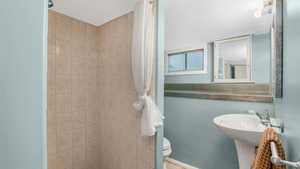 Full bath featuring tiled shower and toilet