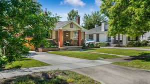 View of front of property with brick siding, a front lawn, a chimney, a porch, and french doors