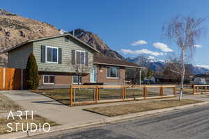 Tri-level home with a mountain view, a fenced front yard, and brick siding