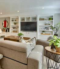 Living area featuring built in shelves and recessed lighting