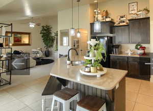 Kitchen featuring decorative light fixtures, a breakfast bar area, open floor plan, lofted ceiling, and light tile patterned floors