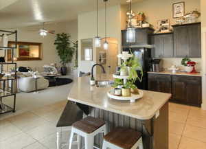 Kitchen featuring hanging light fixtures, a breakfast bar, freestanding refrigerator, open floor plan, and a ceiling fan