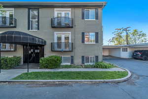 View of front of #10 End Unit with middle floor balcony with brick siding and a carport #B
