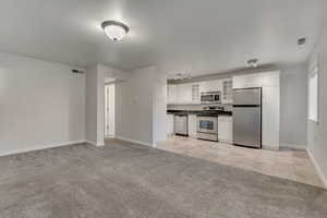 Open floor plan with Kitchen,Dining and Living Room with light carpet, travertine tile, glass insert cabinets, and white cabinets