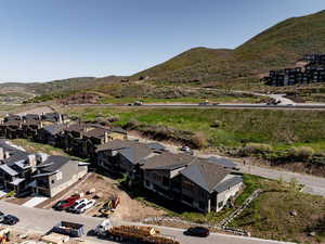 Aerial view of property and surrounding area featuring mountains and nearby suburban area