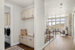 Laundry area with independent washer and dryer, cabinet space, ceiling fan, wood finished floors, and baseboards