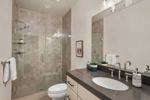 Full bathroom with vanity, a shower stall, and toilet
