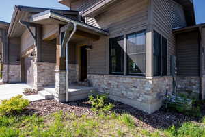 View of side of property featuring stone siding, a garage, and concrete driveway