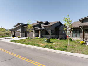 View of front facade featuring stone siding, an attached garage, and concrete driveway