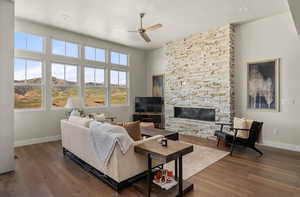 Living room featuring baseboards, a ceiling fan, wood finished floors, a stone fireplace, and recessed lighting