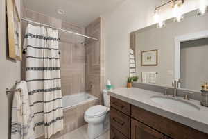 Bathroom with toilet, tile patterned floors, shower / bath combination with curtain, and vanity