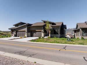 View of front of house featuring stone siding, a garage, concrete driveway, and a mountain view