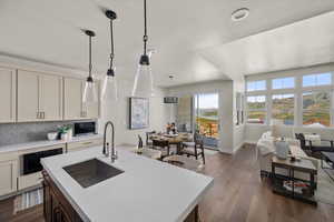 Kitchen featuring a sink, light countertops, backsplash, dark wood finished floors, and baseboards