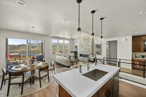 Kitchen featuring a sink, light wood-type flooring, a stone fireplace, light countertops, and recessed lighting