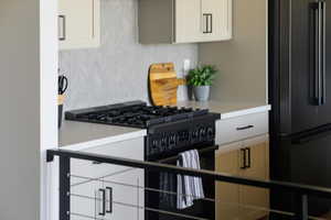 Kitchen featuring black appliances, decorative backsplash, and light countertops