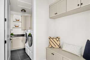 Laundry room featuring cabinet space, washer and clothes dryer, and dark tile patterned flooring
