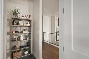 Hallway with wood finished floors, an upstairs landing, baseboards, and recessed lighting