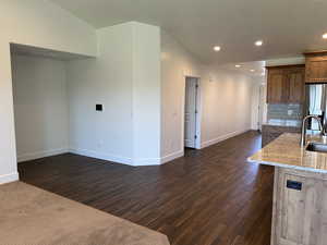 Kitchen with stainless steel refrigerator with ice dispenser, a sink, dark wood-style floors, baseboards, and recessed lighting