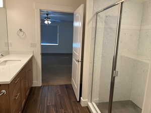 Full bathroom with vanity, ceiling fan, a shower stall, and wood finished floors