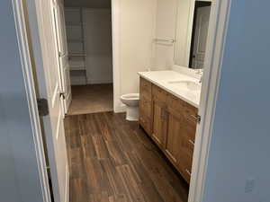 Bathroom with wood finish floors, vanity, toilet, and baseboards