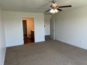 Unfurnished bedroom with carpet, baseboards, a textured ceiling, connected bathroom, and ceiling fan
