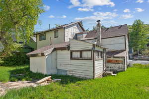 Back of house with a shingled roof and a chimney